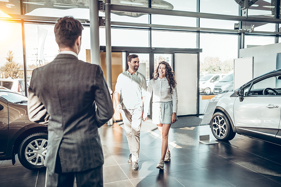 Personal Insurance - Young Couple Walking Into a Car Dealership to Purchase a Vehicle